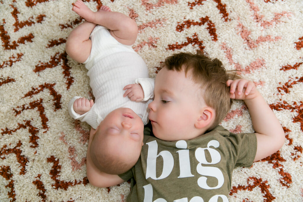 big brother laying on the floor with newborn baby at Columbia, SC newborn session
