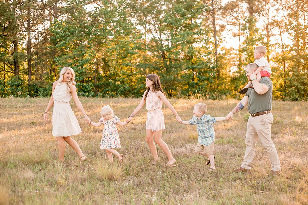 Family of 6 walking through field for family photos with mom the lead