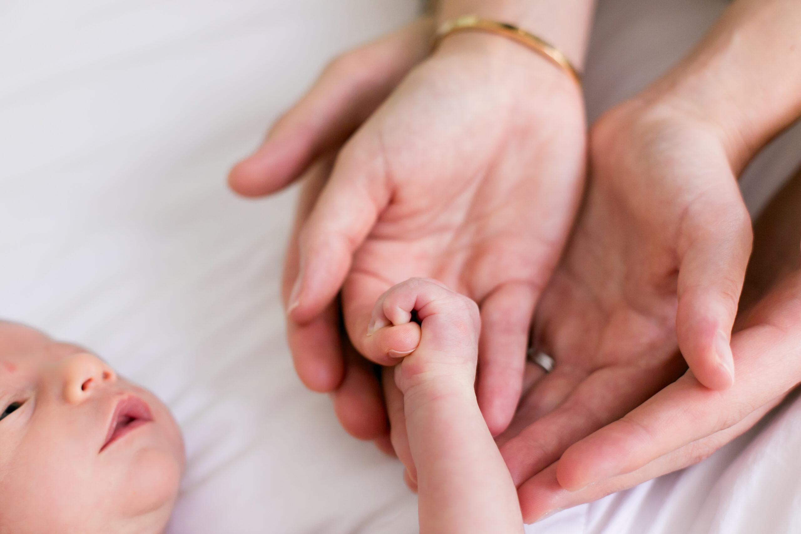a newborn baby grasping the finger of his mom and dad