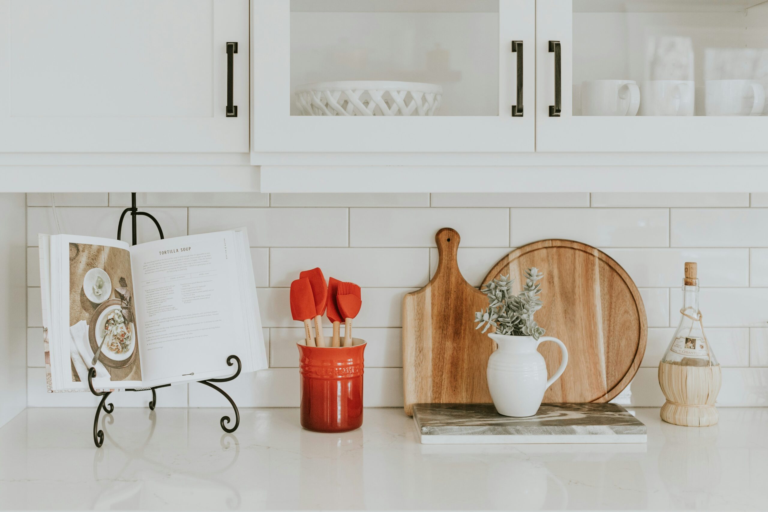 white kitchen counter with a cookbook and cutting board for meal prep