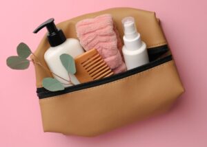 closeup of a brown toiletry bag with lotion, a comb, and a headband peeking out of the bag