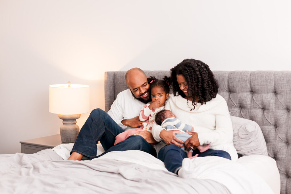 African American family snuggling two kids on a bed at Columbia, SC newborn photo session