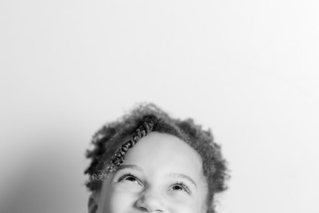 Black and white portrait of a young girl looking upward with a thoughtful expression during a studio portrait session
