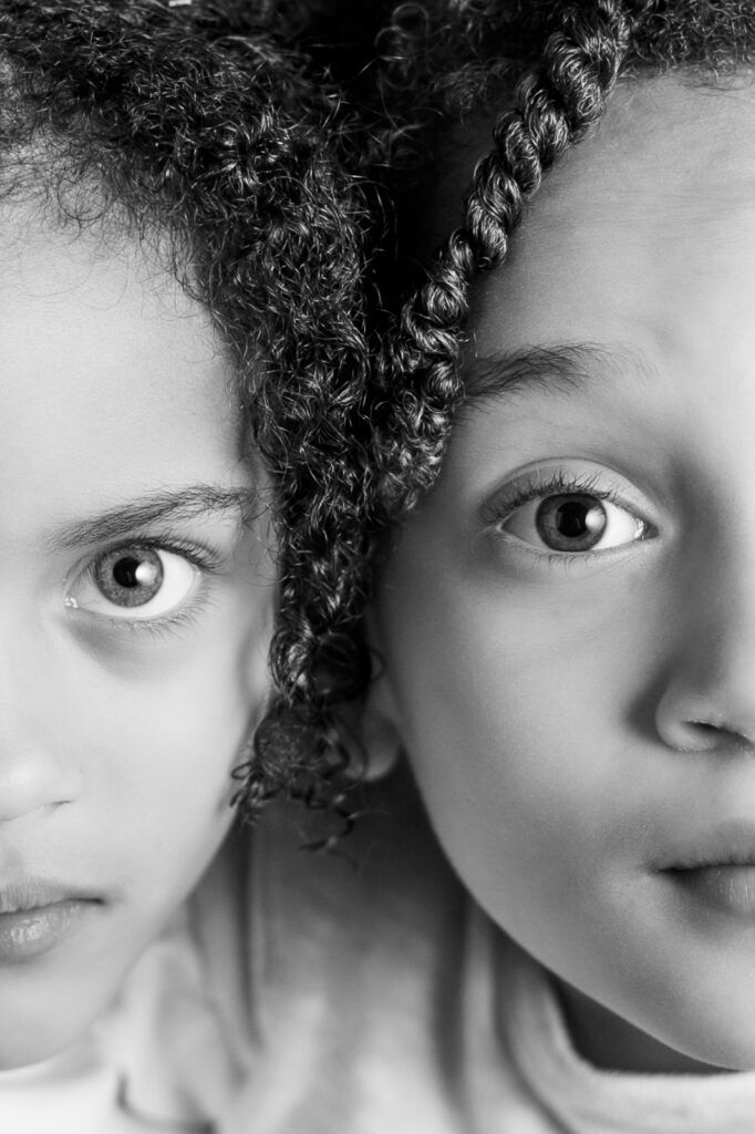 Black and white close-up of two children side by side, highlighting eyes and facial expressions in a personality portrait session